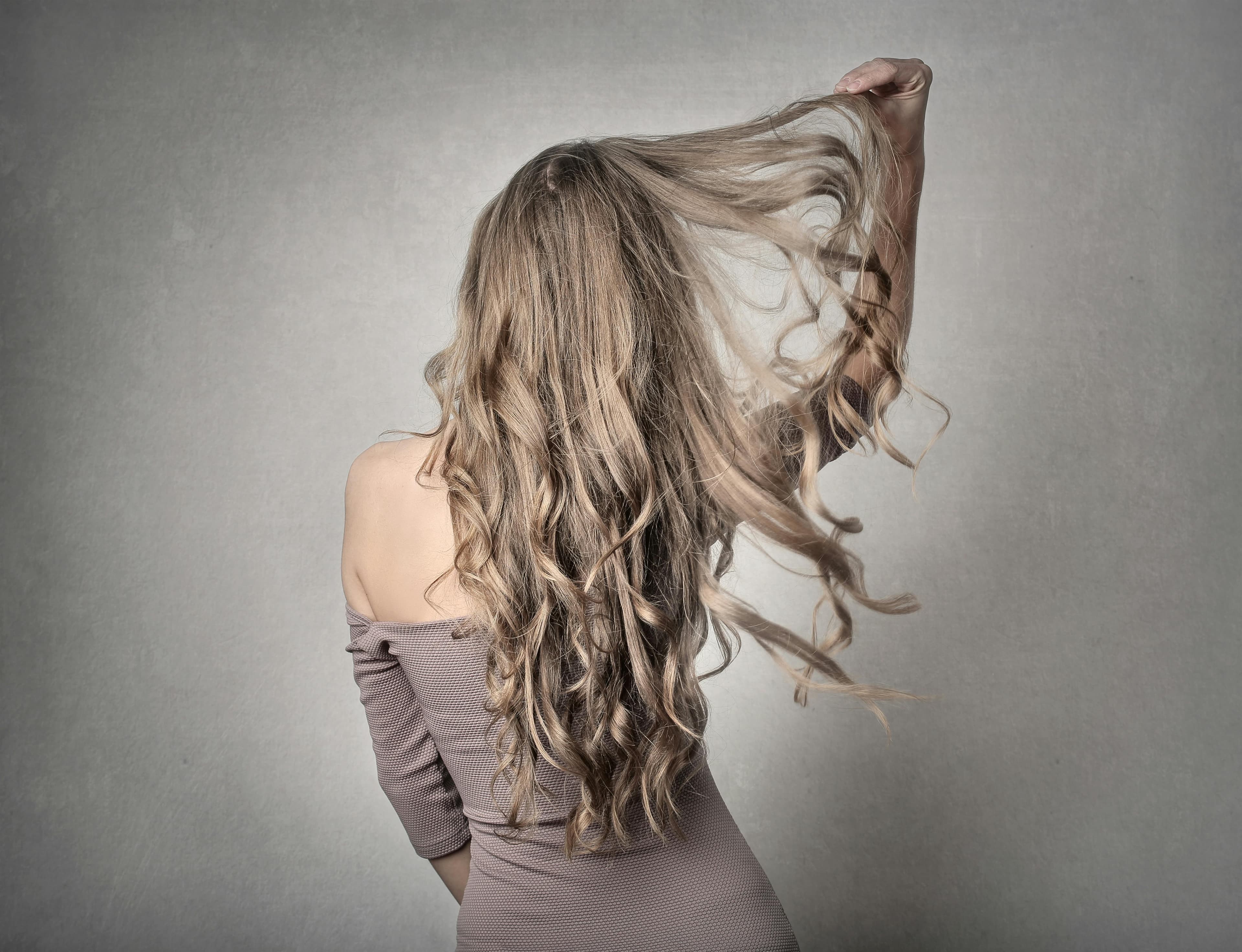 Woman with voluminous frizzy hair showing the effects of Florida humidity — solved with a Brazilian Blowout at Hair by Beth